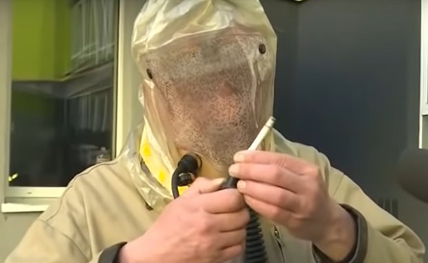 Медик показал как курит в защитном костюме. Фото: скриншот YouTube